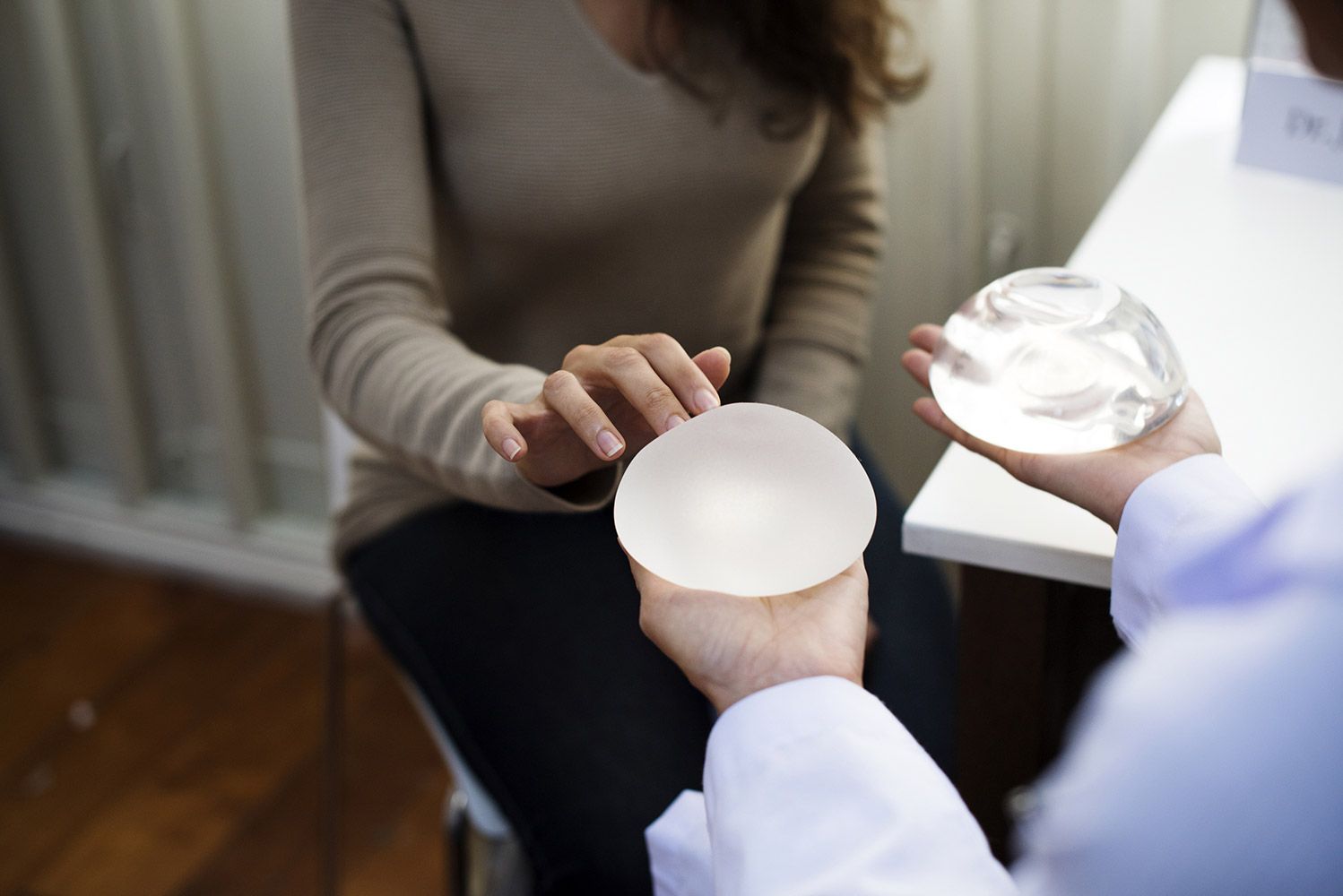 Comparing silicone and saline breast implants during a patient consultation, highlighting differences in look and feel